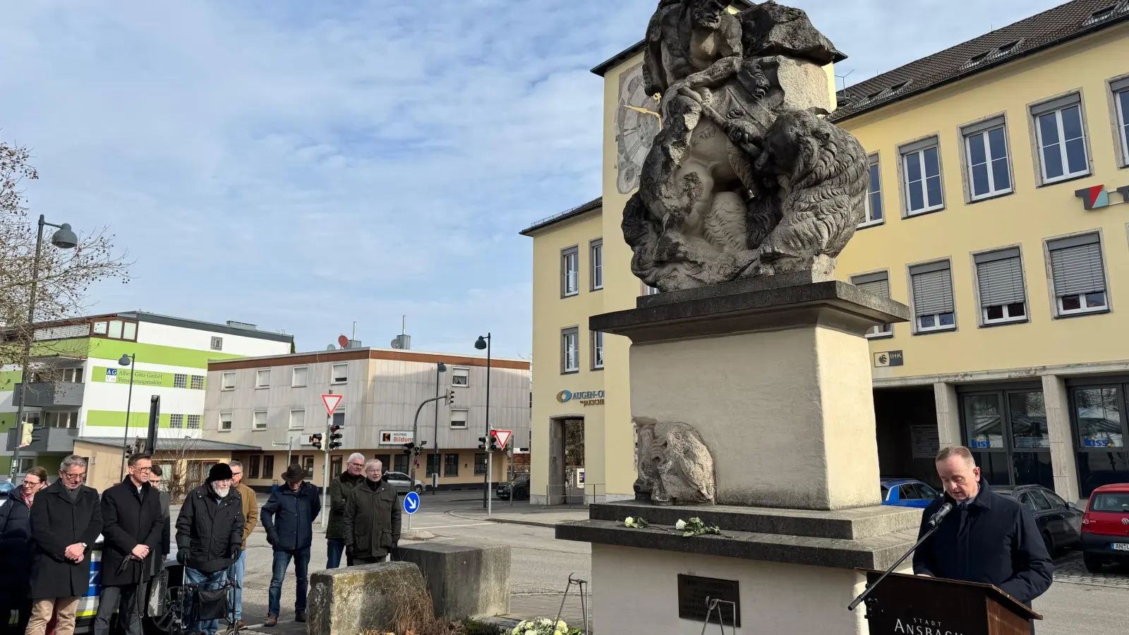 Der Luitpoldbrunnen wurde von den Bomben zerstört, nun erinnern die zusammengefügten Bruchstücke an den Krieg: Oberbürgermeister Thomas Deffner (rechts) las bei der Gedenkstunde vor, was sein Vater am 22. Februar 1945 erlebt und später niedergeschrieben hat. (Foto: Lara Hausleitner)