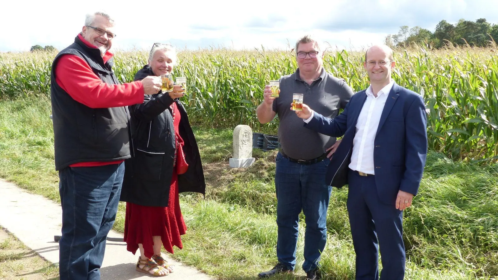 Projektleiter Jürgen Nickel, das Ehepaar Sabine und Andreas Vogt, die den Grenzstein zur Verfügung stellten und Oberbürgermeister Dr. Markus Naser (von links) stießen auf den Stein (im Hintergrund) an. (Foto: Bernhard Heim)