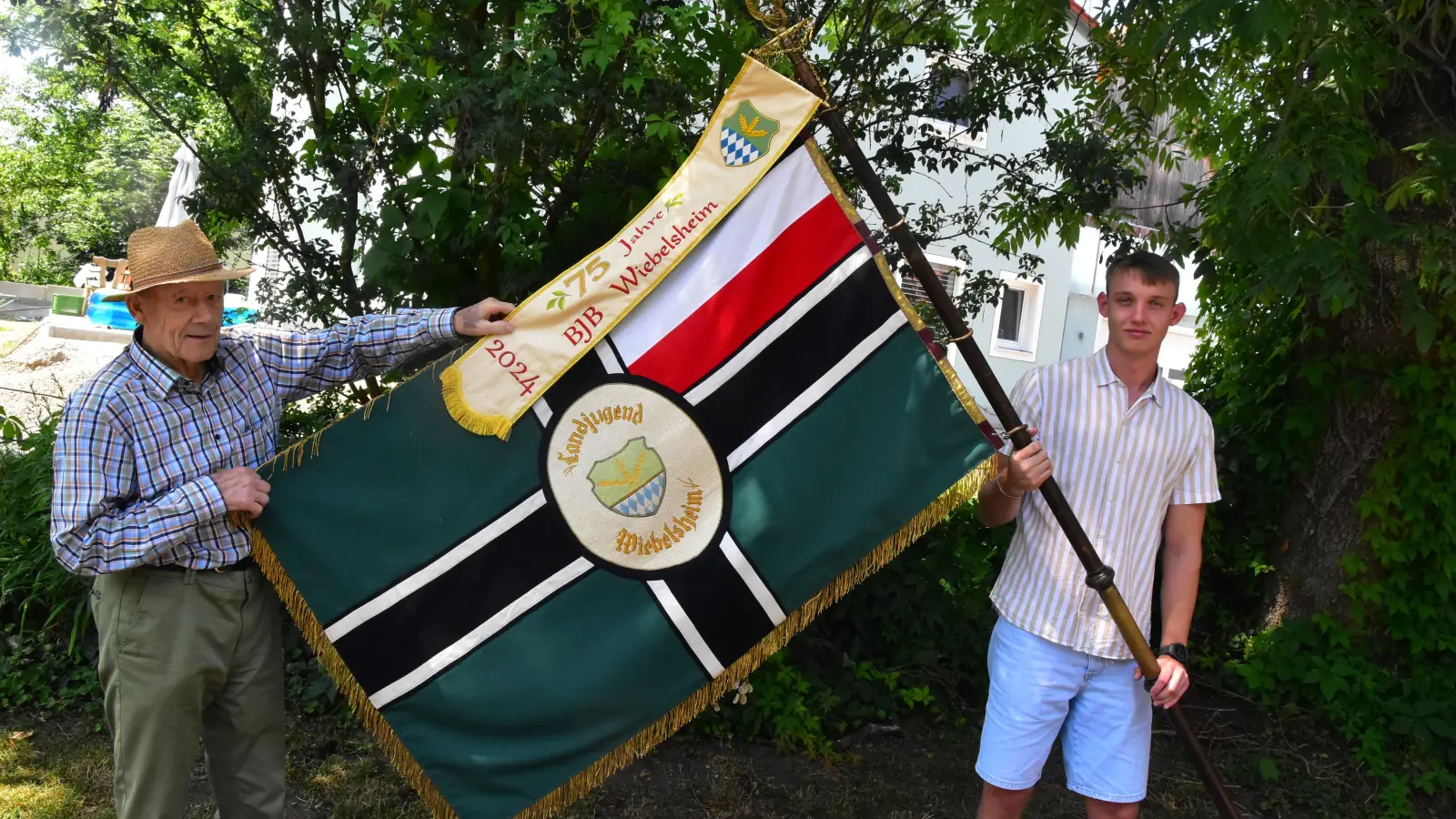 Im Blickpunkt beim Jubiläum: Die fast 100 Jahre alte Fahne der Landjugend mit Vorstandsmitglied Luca Matyssek (rechts) und dem Zeitzeugen aus der Anfangszeit, Georg Dietlein. In der Fahnenmitte haben Mädchen der Gruppe das Hakenkreuz herausgetrennt und das Emblem der Landjugend eingestickt. (Foto: Fritz Arnold)