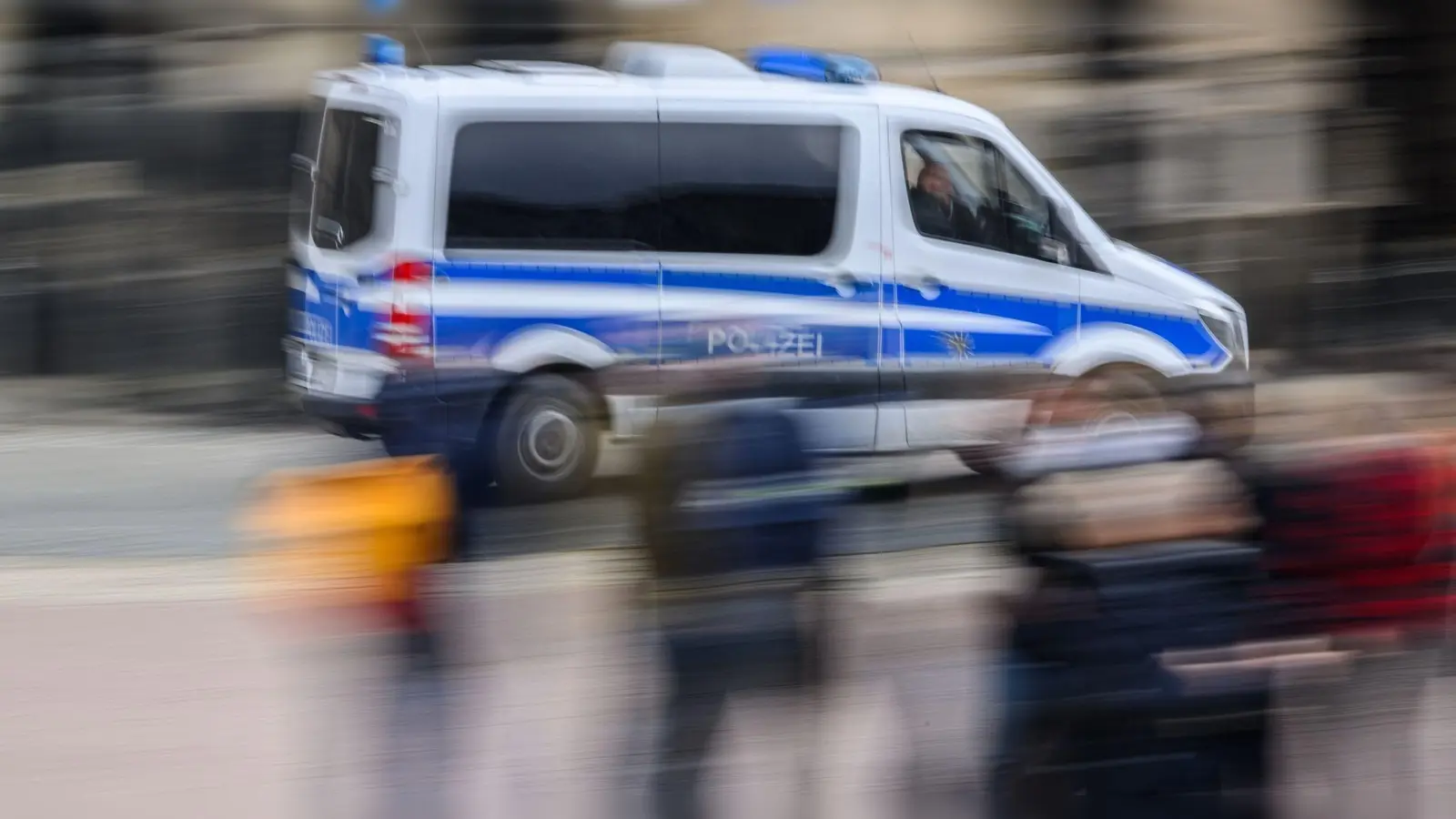 Ein Einsatzwagen der Polizei fährt durch eine Stadt. (Foto: Robert Michael/dpa/Symbolbild)