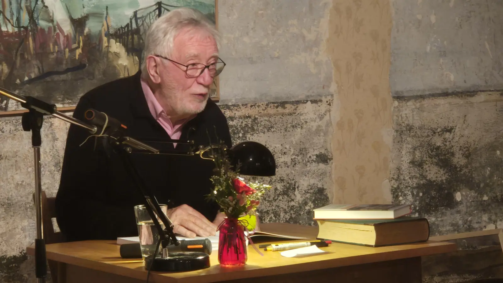 Leselampe, ein kleiner Tisch, ein Mikrofon: Dr. Wolfgang Mück bei seiner Lesung im Saal des Dachsbacher Kaffeehauses im Aischgrund. (Foto: Patrick Lauer)