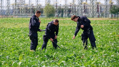 Polizisten suchen die Umgebung ab. (Foto: Henning Kaiser/dpa)