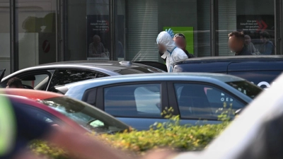 Polizisten führten am Abend einen Mann in einem weißen Anzug aus dem Gebäude, wenig später wurde eine Festnahme vermeldet. (Foto: Armin Weigel/dpa)