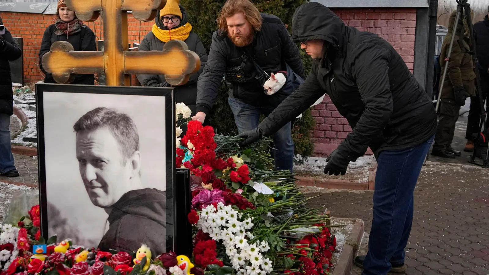 Menschen legen ein Jahr nach dem Tod des russischen Oppositionsführers Alexej Nawalny auf dem Borisowskoje-Friedhof in Moskau Blumen an seinem Grab nieder.  (Foto: Uncredited/AP/dpa)