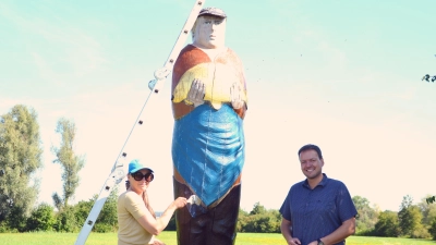 Birgit Jönsson ist mit dem Pinsel gerade dabei, die Holzfigur wieder auf Vordermann zu bringen. Diespecks Bürgermeister Markus Helmreich ist froh, dass das Kunstwerk hergerichtet wird. (Foto: Christa Frühwald )