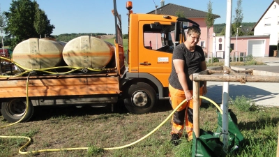 Stadtgärtnerin Monika Begert füllt an der Rothenburger Straße die Wassertaschen einer kürzlich gepflanzten Linde. Im Hintergrund das Bewässerungs-Fahrzeug mit zwei 1500-Liter-Tanks. (Foto: Winfried Vennemann)