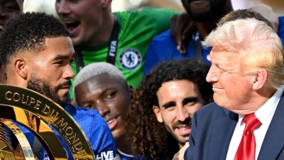 Chelseas Kapitän Reece James (l/vorn) hält auf dem Siegerpodest die Trophäe in den Händen und schaut irritiert zu US-Präsident Donald Trump. (Foto: Sven Hoppe/dpa)