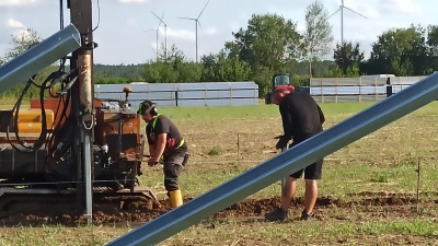 Eine Photovoltaikanlage entsteht: Mit dem Solarpark bei Kettenhöfstetten, dessen Installation begonnen hat, setzt sich der Ausbau der erneuerbaren Energieerzeugung im Gemeindegebiet fort. Im Hintergrund sind die Windräder nahe Birkenfels zu sehen. (Foto: Fritz Arnold)