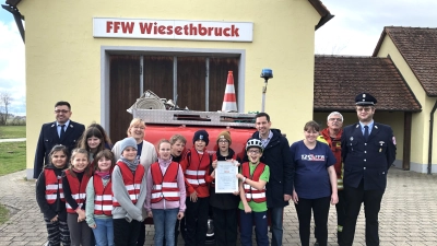 Die Mitglieder der Kinderfeuerwehr der Freiwilligen Feuerwehr Wiesethbruck präsentieren stolz die Gründungsurkunde. Mit dabei: Vorsitzender Florian Weinmann (ganz links), Leiterin Stefanie Klose (Dritte von links) und (von rechts) Kommandant Jörg Schuster, Kreisbrandmeister Peter Schmutter, Betreuerin Lisa Schuster und Bürgermeister Sven Waidmann. (Foto: Johannes Flierl)