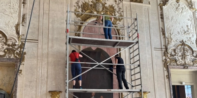 Das über vier Meter hohe Bildnis des Markgrafen Carl Wilhelm Friedrich wird nach oben gehievt, um es an seinem angestammten Platz im Festsaal des Schlosses zu befestigen. (Foto: Lara Hausleitner)