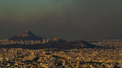 Eine Gesamtansicht von Athen mit dem Akropolis-Hügel (M), während ein Feuer im nördlichen Teil der Stadt brennt. Nur wenige Kilometer nordöstlich der griechischen Hauptstadt bekämpft die Feuerwehr auf einer Fläche von rund 200 Quadratkilometern unzählige Brandherde. (Foto: Petros Giannakouris/AP/dpa-tmn)