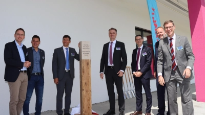 Landrat Dr. Jürgen Ludwig, Bürgermeister Tobias Strauß, Eric Goulet, Dr. Matthias Heinzel, Prof. Dr. Simon Thelen, Ivan Donzelot sowie Christoph Karkossa von Merck (von links) enthüllten die Stele aus Holz und Stein, die an die Eröffnung erinnert. (Foto: Thomas Schaller)