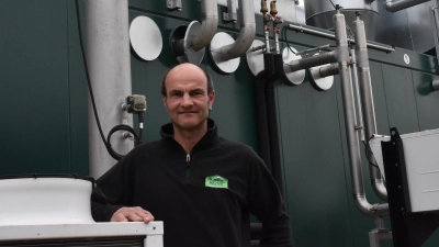 Landwirt Peter Hecht vor seinem Blockheizkraftwerk, das in die Biogasanlage integriert ist und neben mechanischer und elektrischer Energie auch Wärme produziert. (Foto: Silvia Schäfer)
