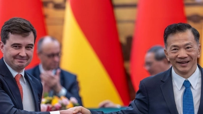 DFL-Geschäftsführer Steffen Merkel (l) und Shen Haixiong, Präsident der China Media Group CMG, nach der Unterzeichnung der Absichtserklärung. (Foto: Michael Kappeler/dpa)