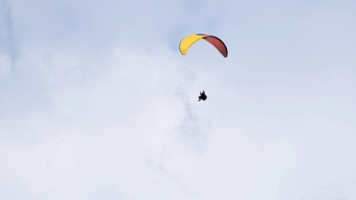 Ein Paraglider fliegt bei teilweise blauem Himmel an einem Berg vorbei. (Foto: Nicolas Armer/dpa)