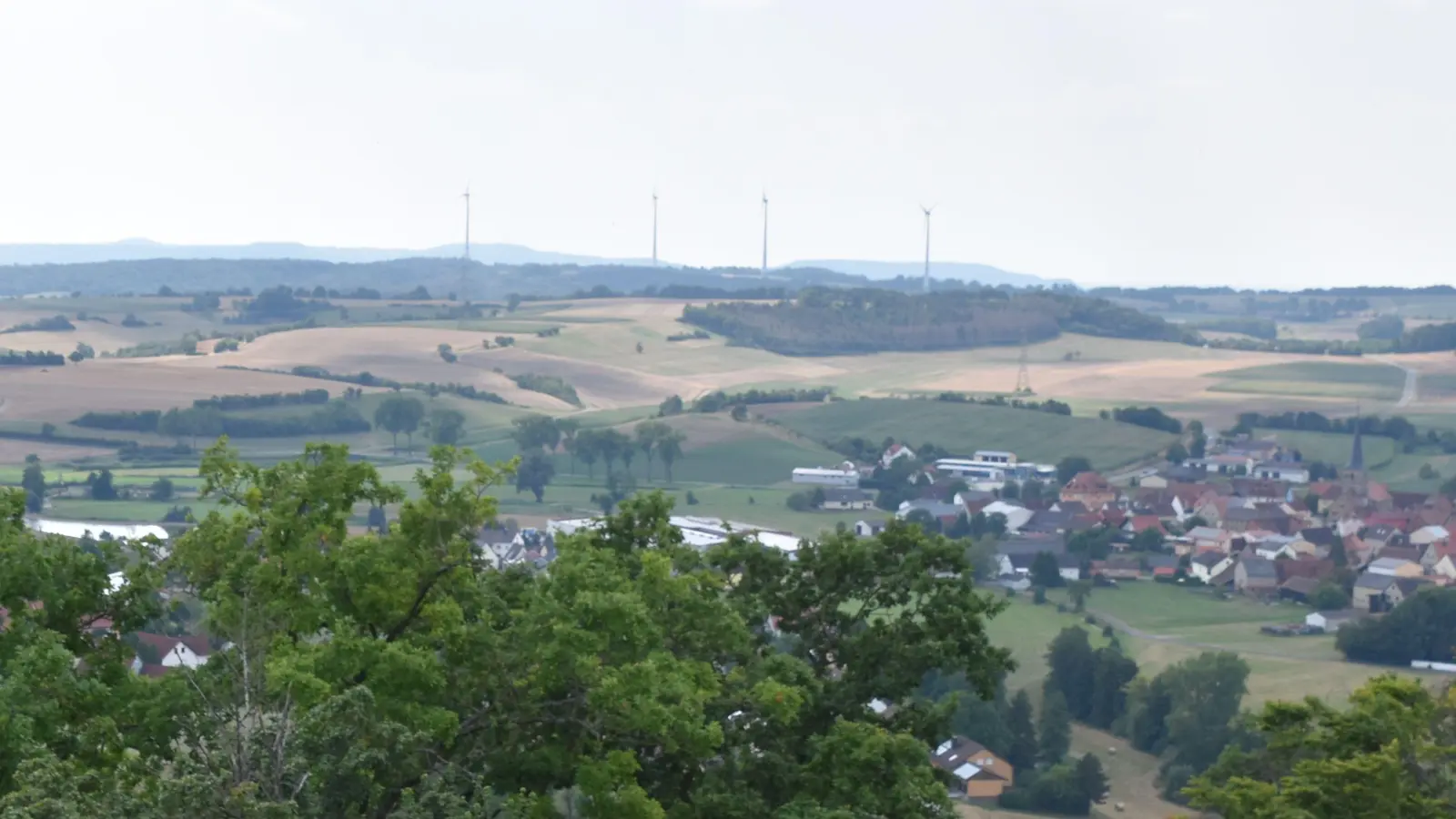 Blick von der Ruine Scharfeneck auf Oberscheinfeld und die in rund vier Kilometer vom Ortskern entfernt stehenden Enzlarer Windräder, von denen drei auf Markt Bibarter Flur stehen und eines auf Oberscheinfelder Gebiet. (Archivfoto: Andreas Reum)