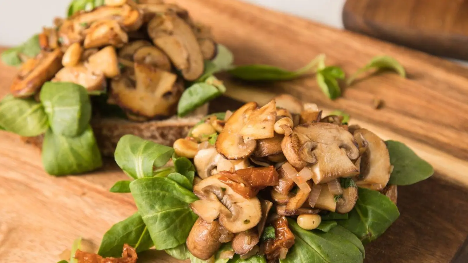 Pilze werden als natürlicher Fleischersatz immer populärer. Statt einer Wurststulle, kann man die Brotscheibe auch mit Champignons, getrockneten Tomaten und Feldsalat belegen. (Foto: Christin Klose/dpa-tmn/dpa)