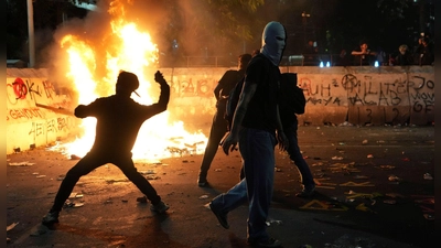 Flammender Protest: Demonstranten bewerfen die Polizei mit Steinen bei einer Kundgebung gegen die aktuelle Haushaltspolitik von Präsident Prabowo in Indonesien.  (Foto: Achmad Ibrahim/AP/dpa)