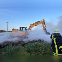 Mit Hilfe von schwerem Gerät zogen die Einsatzkräfte den Strohhaufen bei Markt Nordheim auseinander, um an die Glutnester zu kommen. Eine rauchige Angelegenheit. (Foto: Kreisfeuerwehrverband)