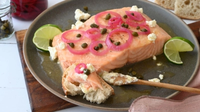 Die Marinade zum gegrillten Lachs sorgt für ein buttrig-süßes Aroma und bildet einen wunderbaren Kontrast zu den sauer eingelegten Zwiebeln und den salzigen Kapern.  (Foto: Julia Uehren/dpa-tmn)
