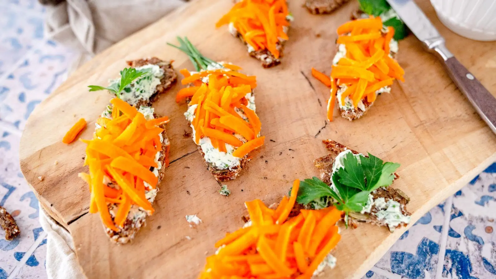 Ob Sauerteig, Pumpernickel oder Toast - für die Möhrenbrote passt alles. Einfach daraus Dreiecke schneiden, Kräuterfrischkäse und Möhrenraspel drauf. (Foto: gernekochen.de/dpa-tmn)