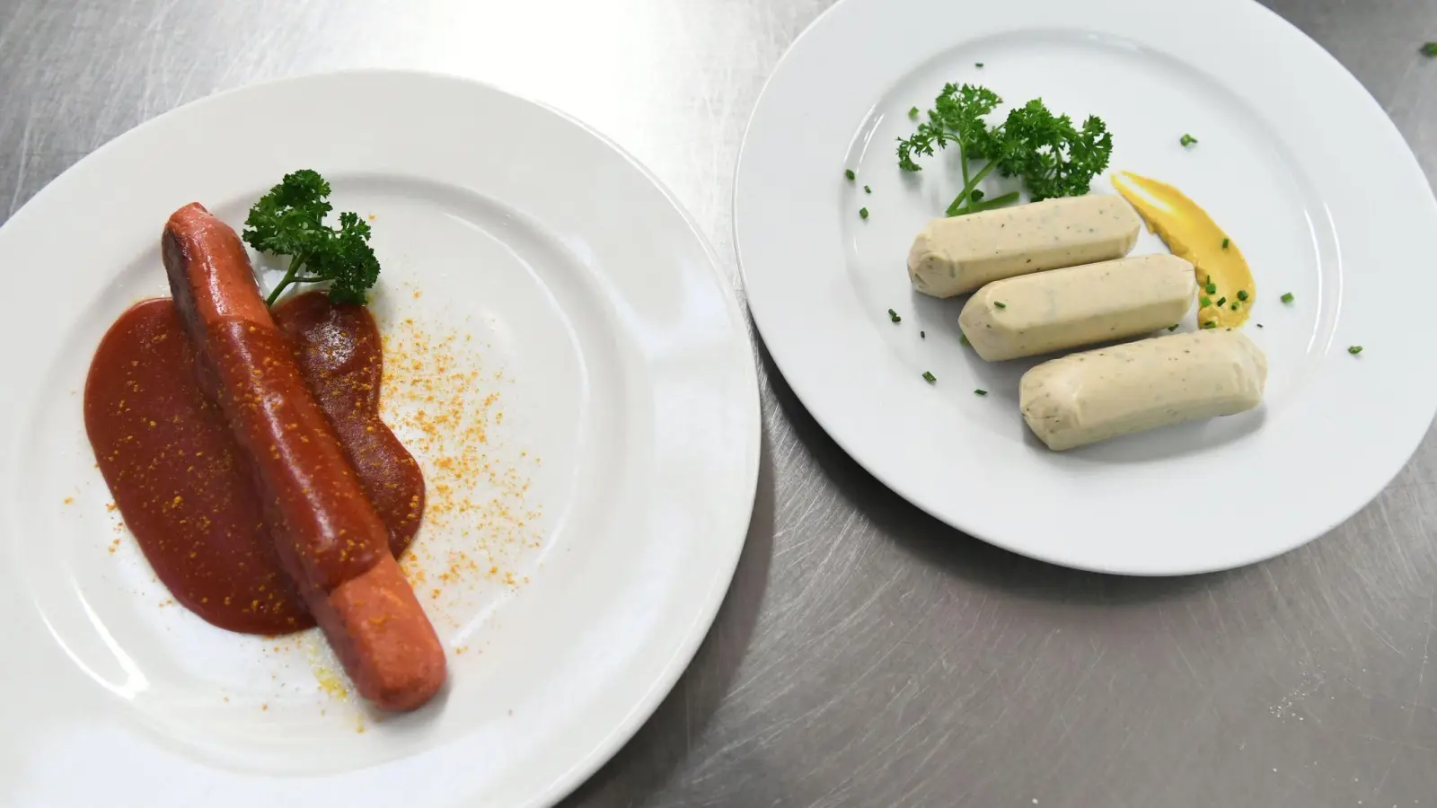 Eine vegane Currywurst und vegane Weißwürste liegen auf Tellern an der Essensausgabe im Hofbräuzelt auf dem Oktoberfest. (Foto: Felix Hörhager/dpa)