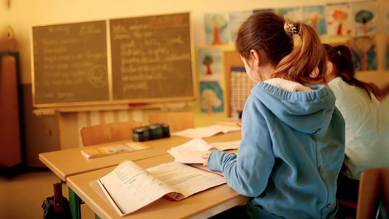 Damit sich links- und rechtshändige Schulkinder nicht mit den Ellenbogen ins Gehege kommen, sollte ein Linkshänder auf der linken Seite und der Rechtshänder auf der rechten Seite daneben sitzen. (Foto: Oliver Berg/dpa/dpa-tmn)
