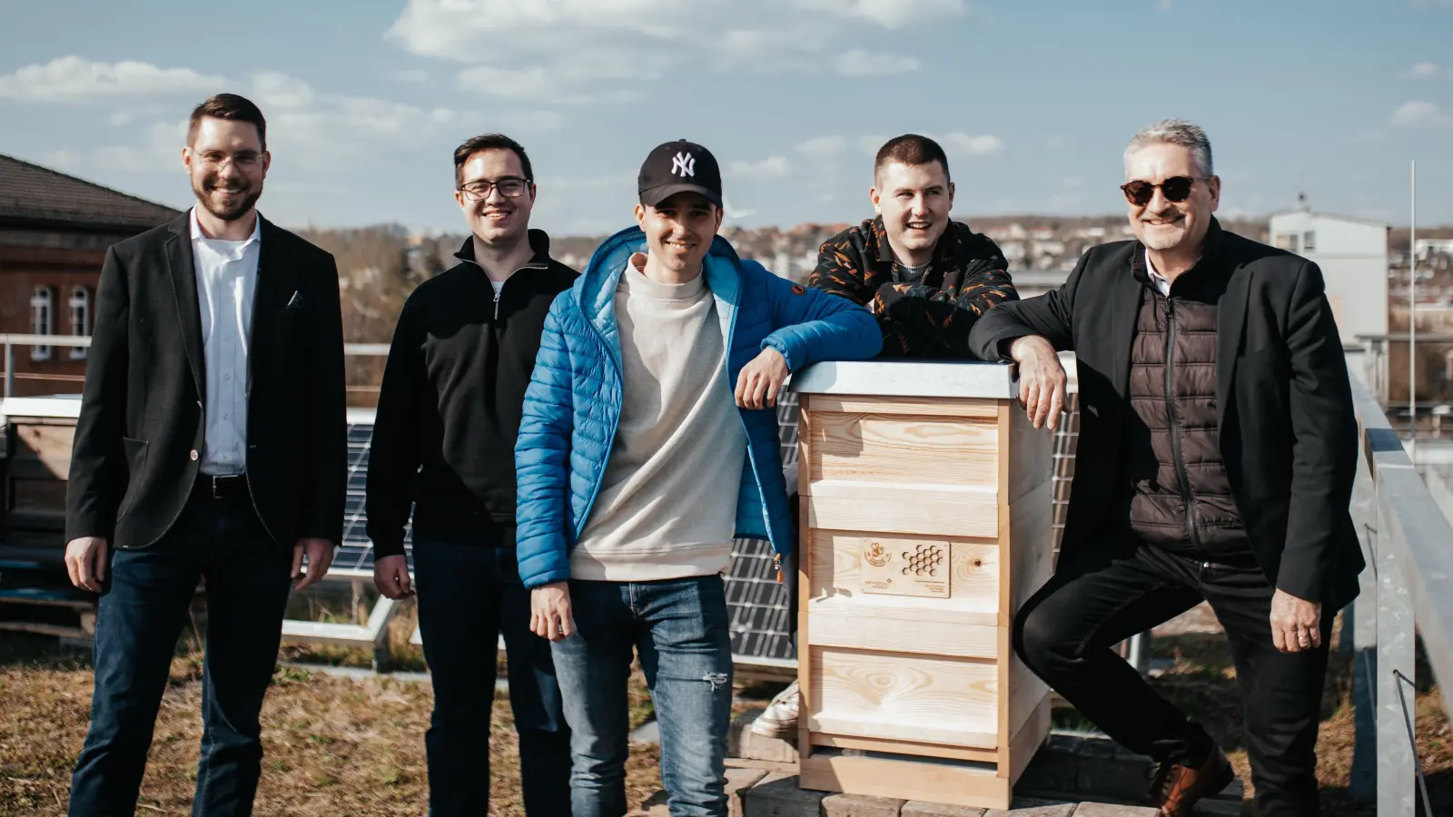 Professor Dr. Simon Gollisch (links) und Professor Stefan Weiherer (rechts) gefällt das: Pascal Kelm, Jannis Grundmann und Henri Reisslein (von links) übergeben auf dem Dach eines Hochschulgebäudes ein Domizil für Bienen. Dieses bauten sie im Rahmen ihres Studiums. (Foto: Hochschule Ansbach/Anna-Sophia Sackwitz)