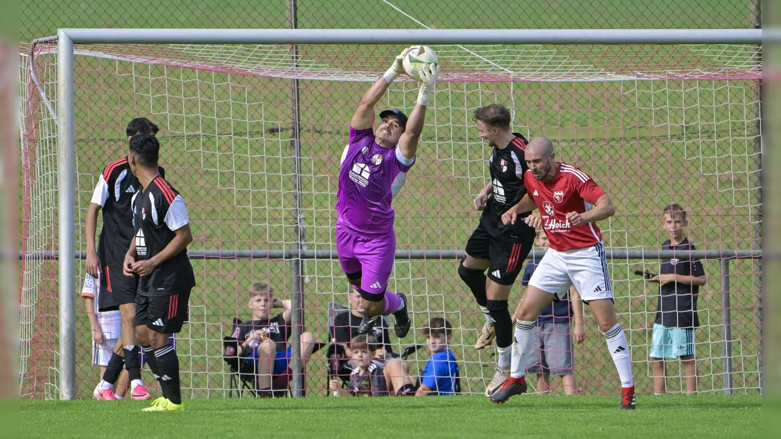 Nikolai Schubert, der Torwart des TV Leutershausen, fängt den Ball vor Patrick Kahle (im roten Trikot). Der TVL siegte mit 2:1 in Schalkhausen und empfängt am Samstag den FSV Stadeln II, der SVS muss am Sonntag nach Losaurach. (Foto: Martin Rügner)