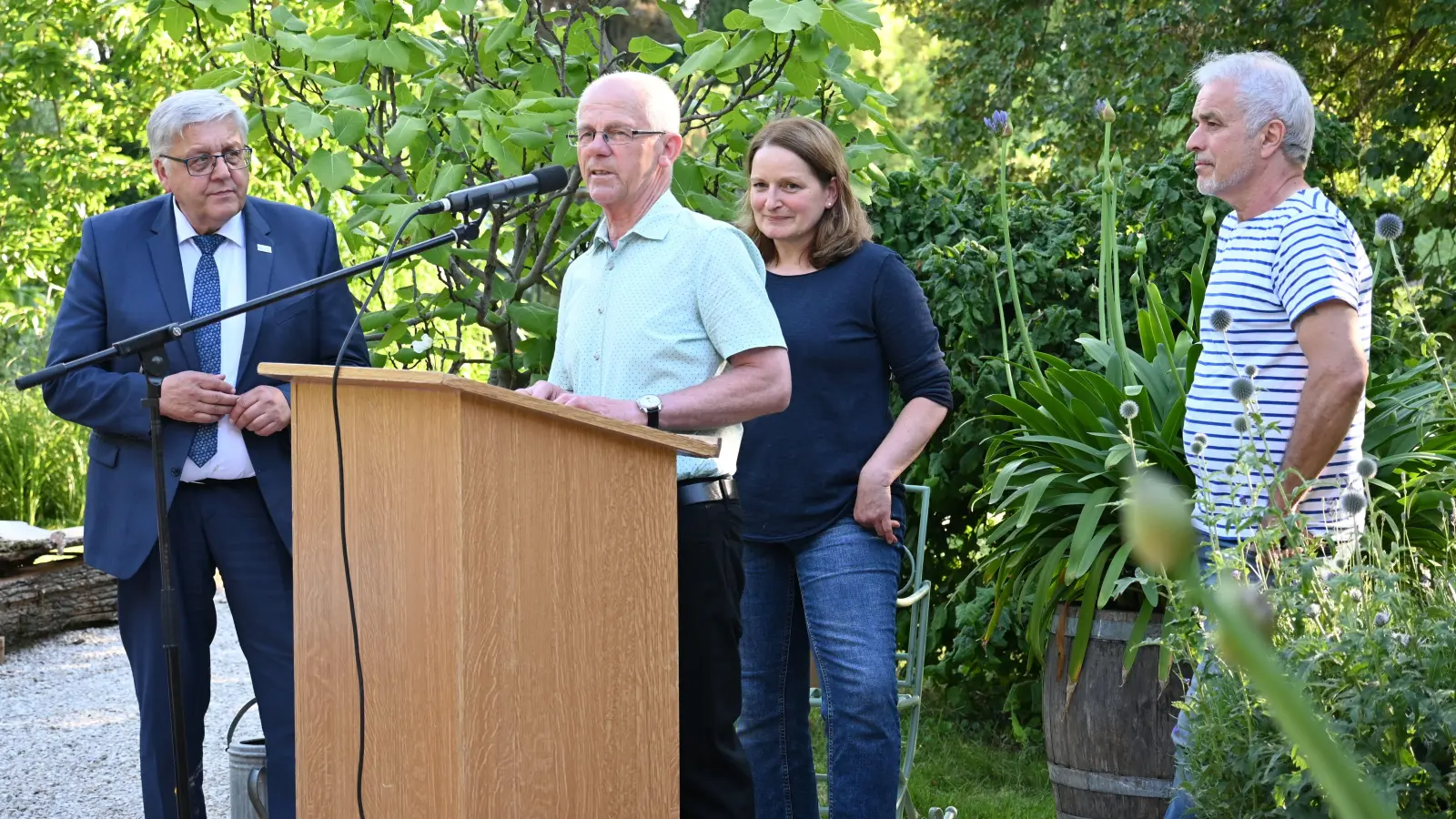 Lara Nalezinski und Richard Erlbacher freuen sich, dass sie ihr Mühlenanwesen für die Öffentlichkeit öffnen können. Am Mikrofon Gerhard Durst, Vorsitzender des Bezirksverbandes für Gartenbau und Landespflege, ihm lauscht (links) Landrat Helmut Weiß. (Foto: Judith Marschall)