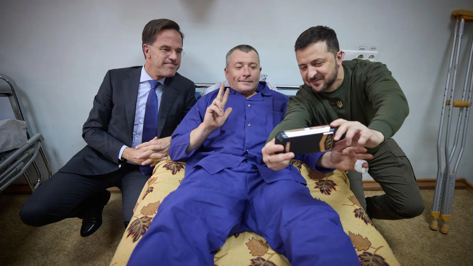 Ein verwundeter ukrainischer Soldat macht ein Selfie mit Präsident Wolodymyr Selenskyj und dem niederländischen Regierungschef Mark Rutte, der zu Besuch in der stark von russischen Luftangriffen betroffenen Hafenstadt Odessa ist. (Foto: Uncredited/Ukrainian Presidential Press Office/AP)