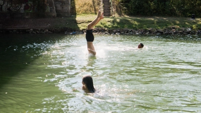 Ein junger Mann springt kopfüber zur Abkühlung von einer Brücke in einen Kanal. Das Springen von Schleusen, Wehren und Brücken endet immer wieder tödlich. (Foto: Julian Stratenschulte/dpa)