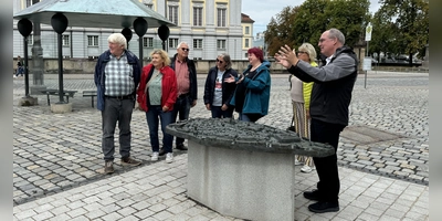 Die erste Station dieser öffentlichen Stadtführung mit dem Historiker Alexander Biernoth (rechts) bildete das Bronze-Tastmodell des Zentrums auf dem Schlossplatz gegenüber der Residenz. (Foto: Oliver Herbst)