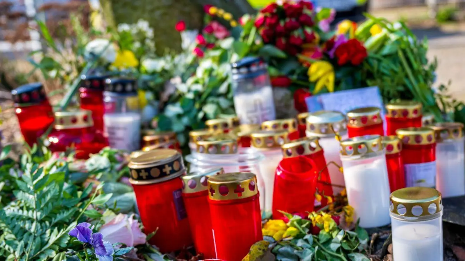 Blumen und Kerzen liegen vor einem Einfamilienhaus in Scheeßel. (Foto: Sina Schuldt/dpa)