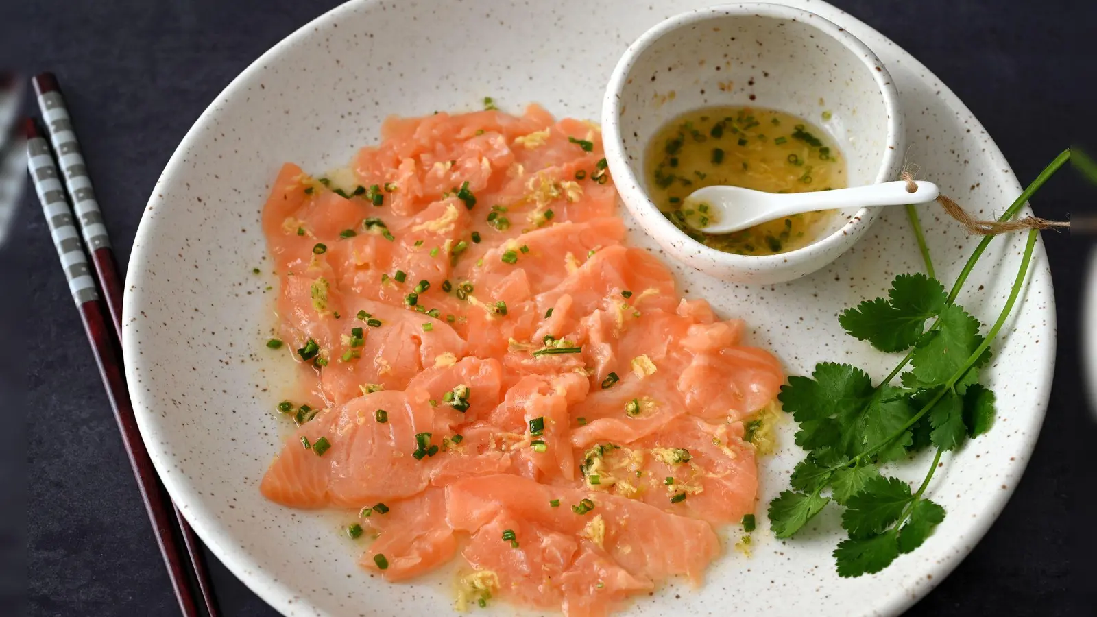 Wenn man das Lachs-Carpaccio mit dem asiatischen Dressing beträufelt, wird die Farbe des Fischs etwas heller. (Foto: Julia Uehren/loeffelgenuss.de/dpa-tmn)