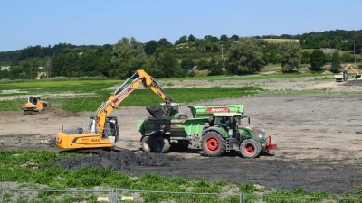 Bagger befördern die in Erdbecken getrockneten Sedimente in Muldenkipper. Links schiebt eine Raupe noch im flacheren Bereich des Sees Ablagerungen ab. (Foto: Gerhard Krämer)