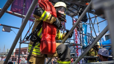 Der Feuerwehrmann Philipp Reumann von der Freiwilligen Feuerwehr Eckwarden steigt bei der „Firefighter Combat Challenge“ in Bremerhaven mit einem Schlauch auf einen Turm. (Foto: Focke Strangmann/dpa)