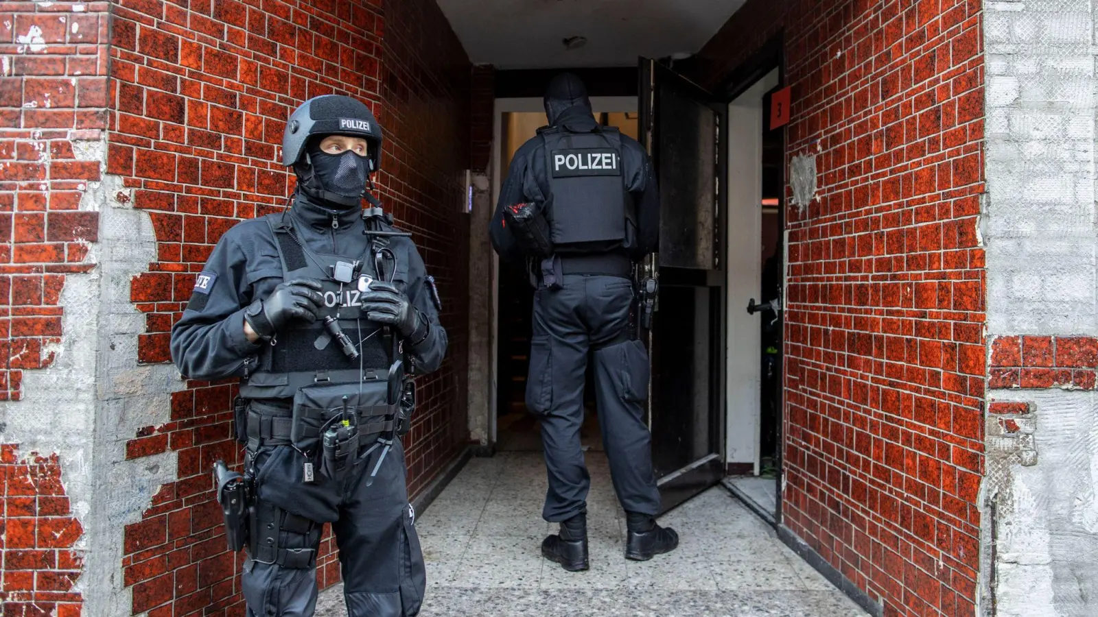 Polizisten stehen in einem Hauseingang im Stadtteil Laar. (Foto: Christoph Reichwein/dpa)