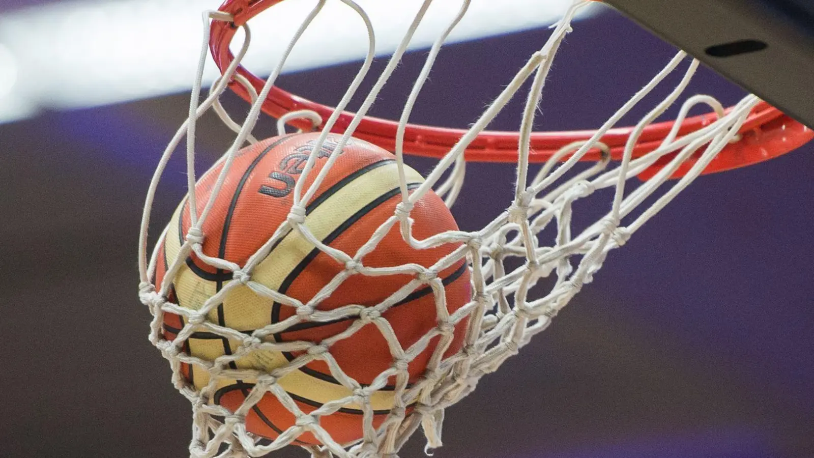 Ein Basketball fällt in den Basketballkorb. (Symbolbild: picture alliance / dpa)