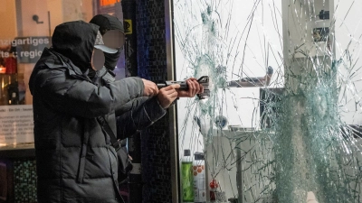 Zwei Männer stehlen durch die eingeschlagene Scheibe eines Waffengeschäft eine Waffe.  (Foto: Andreas Arnold/dpa)