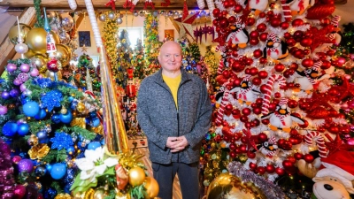 Thomas Jeromin steht inmitten von Weihnachtsbäumen in seinem Haus im Landkreis Schaumburg.  (Foto: Julian Stratenschulte/dpa)