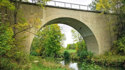 Die über die Tauber führende alte Bahnbrücke in Gebsattel und der angrenzende Bahndamm könnten bei Hochwasserereignissen zu einer Verlangsamung des Abflusses beitragen. Hier hofft die Gemeinde auf genaue Berechnungen, um über sinnvolle Gegenmaßnahmen diskutieren zu können. (Foto: Jürgen Binder)
