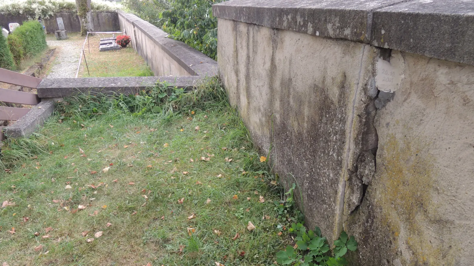 Die Westmauer in Friedhof St. Michaelis in Feuchtwangen ist in ihrem südlichen Bereich akut einsturzgefährdet. Risse wie der rechts im Bild sind auch in dem tiefer gelegenen Abschnitt – hinten, wo der direkte Zugang gesperrt ist – deutlich zu erkennen. Stellenweise neigt sich die Mauer dort bereits nach außen. Der Schäden sind entstanden, weil die steile Böschung, auf der die Mauer steht, außerhalb des Gottesackers abrutscht. (Foto: Peter Zumach)