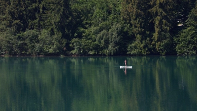 Eine Frau paddelt auf einem Stand-up-Paddle-Board über den Forggensee.  (Foto: Karl-Josef Hildenbrand/dpa)