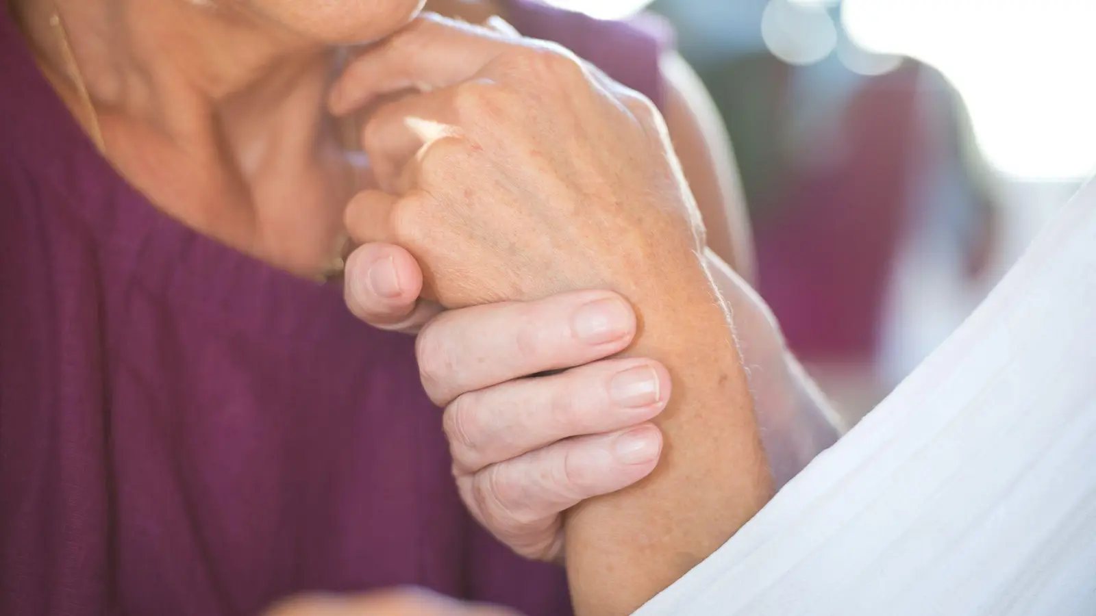 Eine Frau hält die Hand ihres an Demenz erkrankten Mannes. (Foto: Daniel Naupold/dpa)