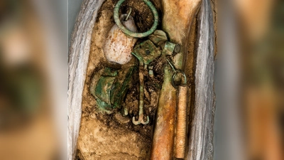 Zu den Grabbeigaben gehörten unter anderem ein Walnussanhänger, gelochte Münzen und Bronzeschlüssel. (Foto: BLfD/dpa)