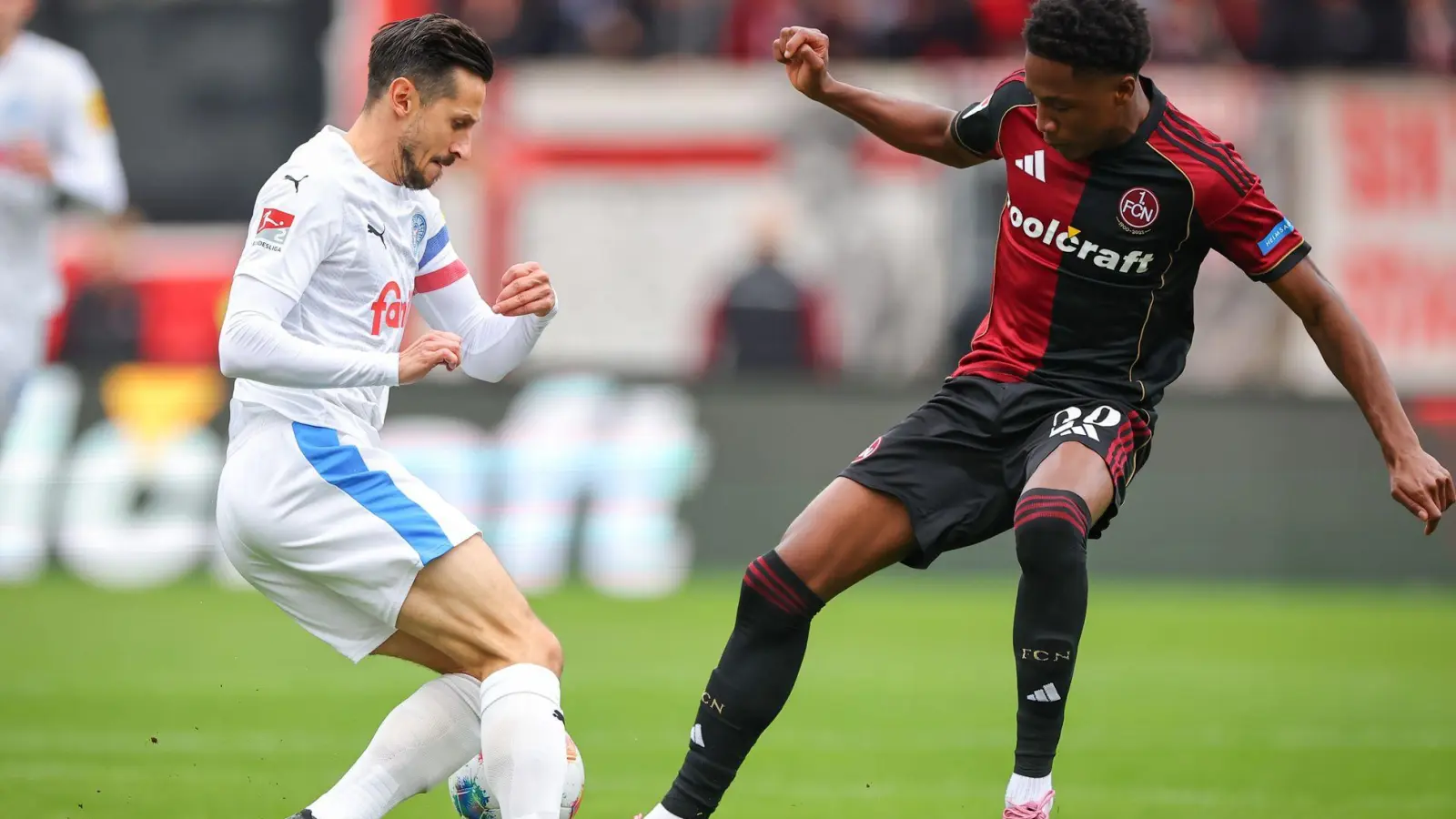 Kiel-Kapitän Steven Skrzybski (links) und Pape Demba Diop von Nürnberg kämpfen um den Ball. (Foto: Daniel Karmann/dpa)