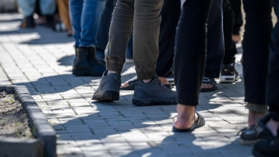 Flüchtlinge stehen in einer Erstaufnahme-Einrichtung in einer Schlange (Symbolbild). Der Stadtrat von Burg fordert im Brief an Kanzler Scholz unter anderem eine Rückführung abgelehnter Asylbewerber und eine Erweiterung der sicheren Herkunftsländer. (Foto: Hannes P Albert/dpa)