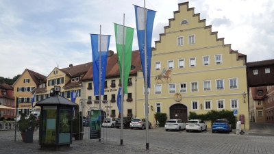 Das ehemalige Postgebäude an Feuchtwangens Marktplatz (rechts): Im Erdgeschoss kommen jetzt alle Nutzer des direkt gegenüber stehenden Alten Rathauses so lange unter, bis dieses fertig saniert ist. Der Info-Pavillon links und die Fahnen stehen vor den bisherigen Räumen der Tourist-Information. (Foto: Peter Zumach)