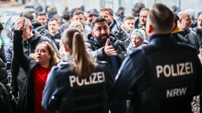 Aufgebrachte Kunden diskutieren vor der Sparkassenfiliale mit Polizeibeamten (Archivfoto) (Foto: Christoph Reichwein/dpa)